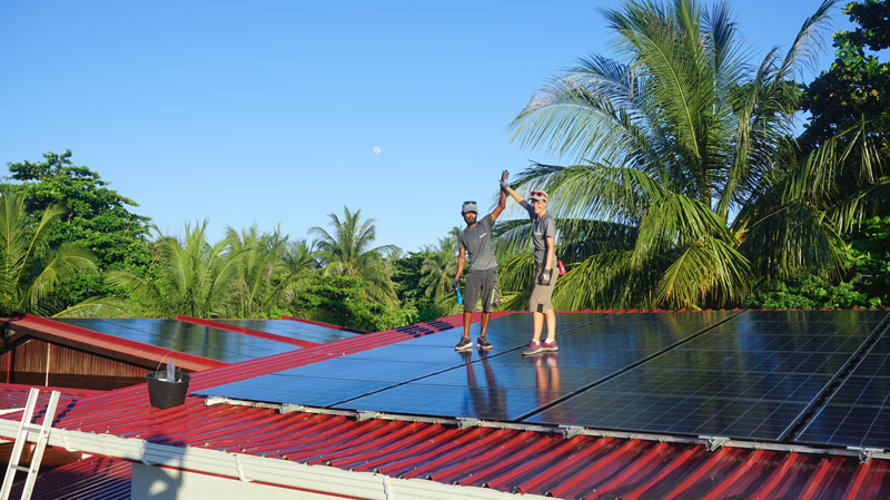 Swimsol Solar installers high-fiving upon on a roof with a PV installation